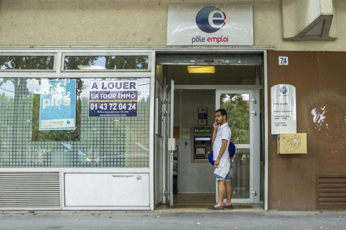 A man stands in the entrance of an employment center in Paris. The number of jobless workers in the 17-nation Eurozone dropped slightly in June, the European Union reported.