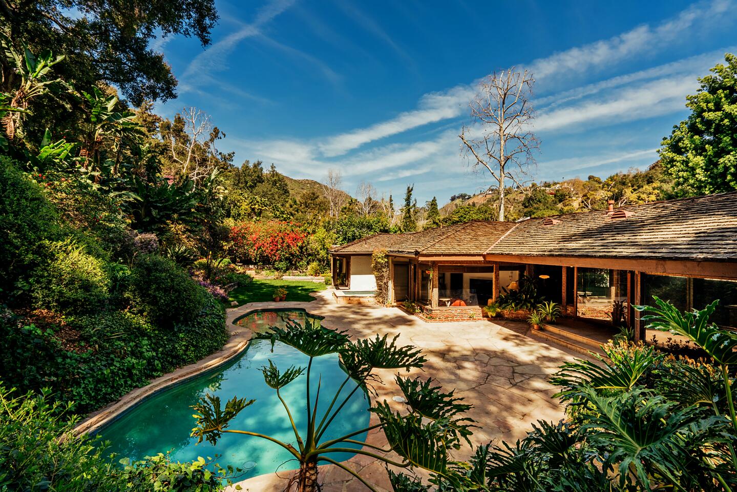 Offering a design palette of wood, brick and stone, the quiet ranch retreat sits on half an acre with colorful gardens and glass-filled living spaces.