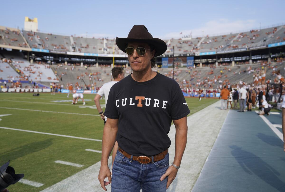 Matthew McConaughey walks the sidelines of a football field wearing a cowboy hat and a T-shirt that says "Culture"