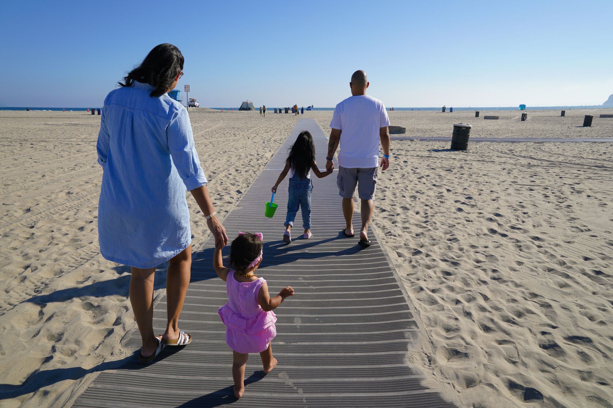 a family holds each other hands while walking down a path to the beach
