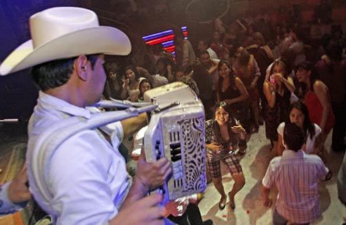 Alfredo Madrigal, a member of Herederos de la Frontera, plays accordion for admiring fans at the Baby Rock club in Tijuana. His group specializes in traditional Norteño-style ballads.