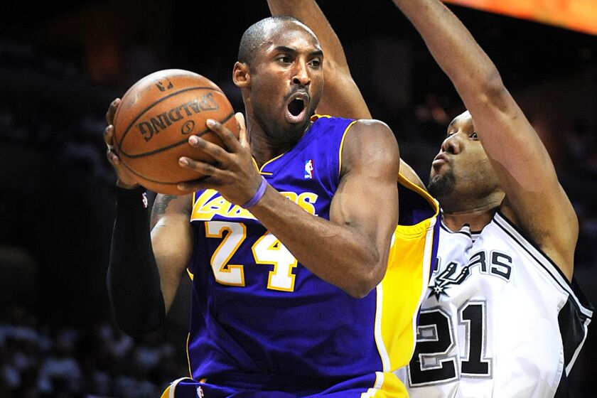 Spurs forward Tim Duncan forces Lakers guard Kobe Bryant, left, to pass after driving to the basket during a playoff game in 2008.