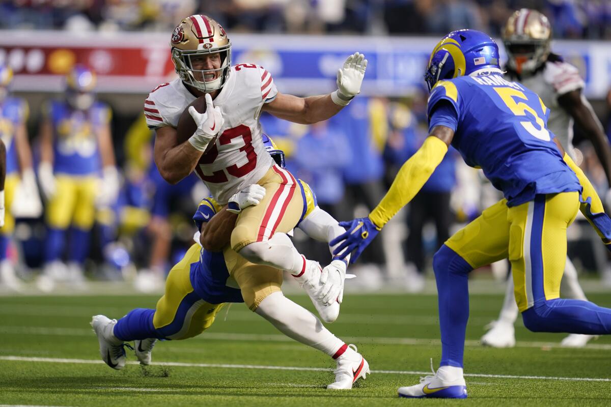 49ers running back Christian McCaffrey is tackled by Rams safety Taylor Rapp in front of cornerback Jalen Ramsey.