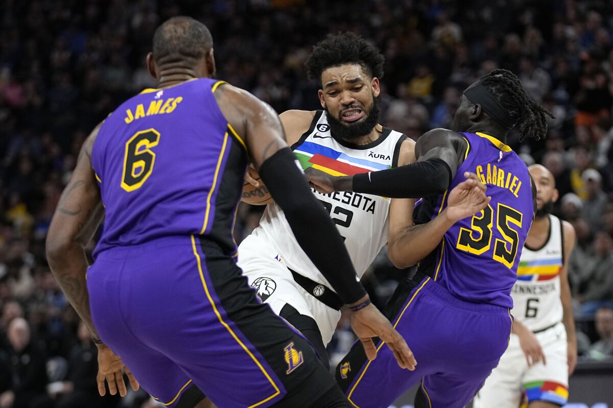 Minnesota Timberwolves center Karl-Anthony Towns works toward the basket while defended by Los Angeles Lakers forward LeBron James (6) and forward Wenyen Gabriel (35) during the first half of an NBA basketball game Friday, March 31, 2023, in Minneapolis. (AP Photo/Abbie Parr)