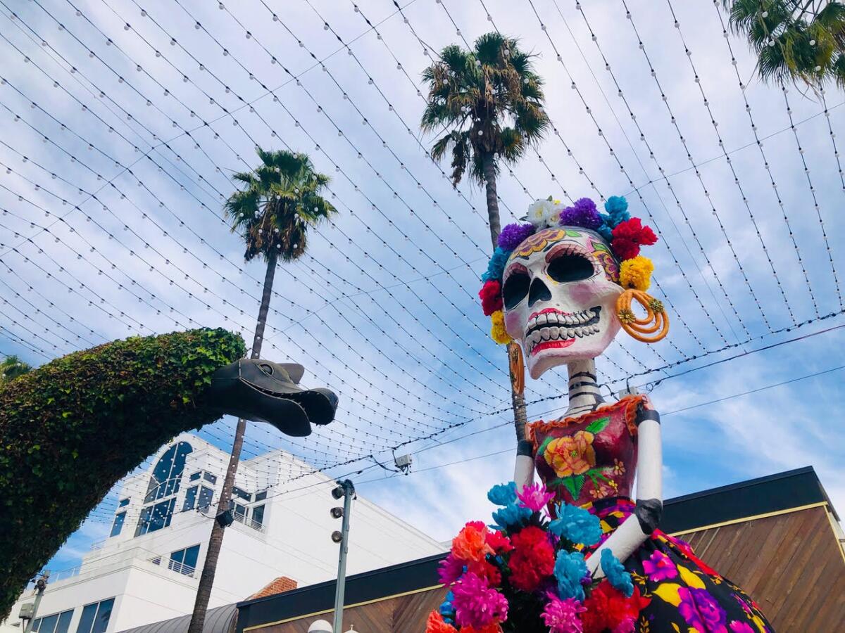 La Catrina sculpture in front of palm trees.