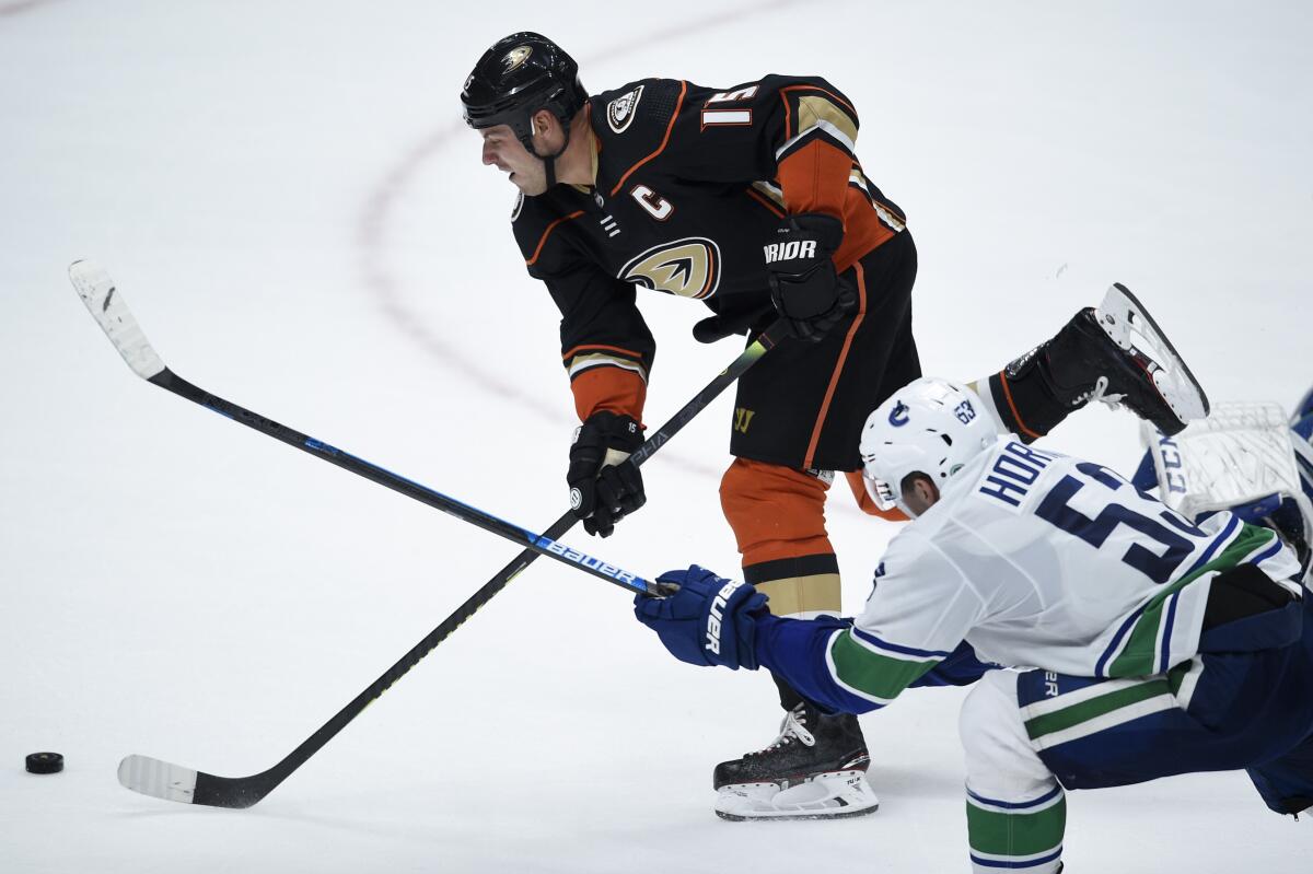The Ducks' Ryan Getzlaf, top, scores the game-winning goal as he gets past the Canucks' Bo Horvat during overtime at Honda Center.