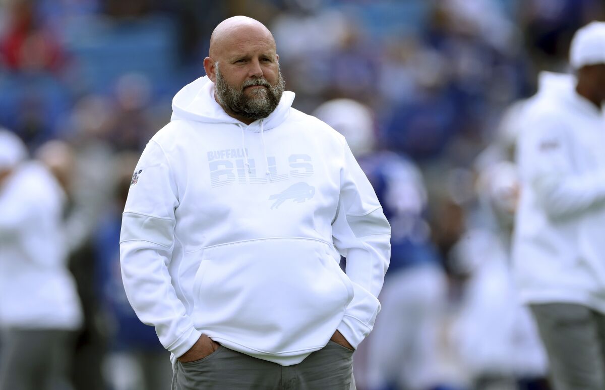 Brian Daboll, in Buffalo Bills sweatshirt, stands on the sideline with his hands in his pockets.