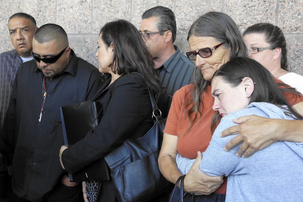 Relatives comfort a grieving Rudy Coronado, second from left, the father of three slain girls.