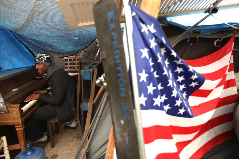 WEST LOS ANGELES, CA - OCTOBER 30, 2021 - - Iraq war veteran Lavon Johnson, 35, plays his piano inside his tent along Veterans Row on a Saturday morning along San Vicente Boulevard in an unincorporated area near Brentwood on October 30, 2021. Johnson was stationed in Fort Hood and deployed to Iraq in 2006 and 2007 and has been living homeless on Veterans Row for about a year. Asked why he thought it took so long to get the veterans help, Johnson is quick to answer: "Pride. Money. Nobody wants to admit a mistake was made." He will be relocated to an individual tent on the VA campus before clearing of the encampments begins on November 1. Veterans Affairs Secretary Denis McDonough, who visited the encampment in October, said last week that the about 40 veterans from Veterans Row would be housed by November. (Genaro Molina / Los Angeles Times)
