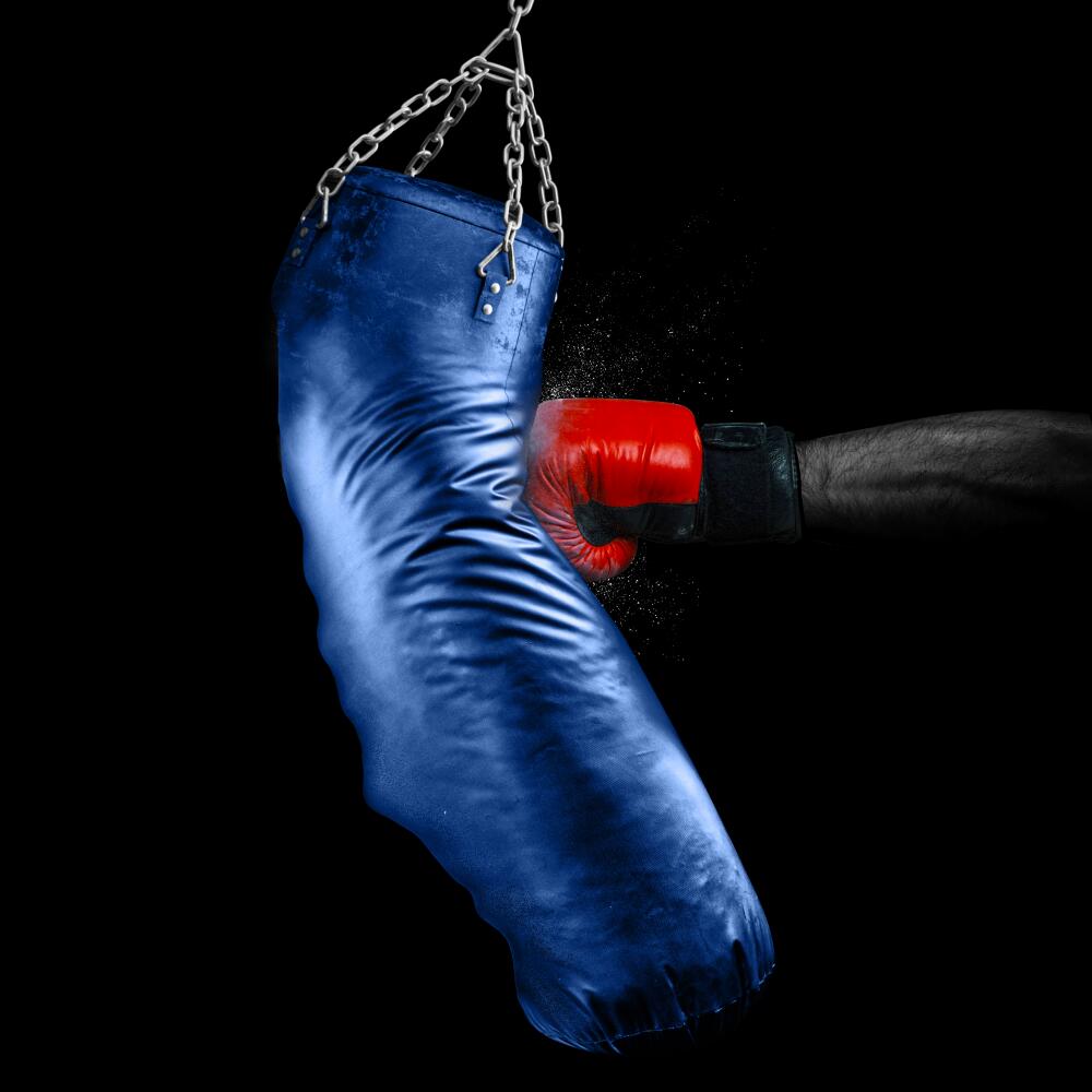 photo illustration of a blue heavy bag in the shape of california being punched by a red boxing glove