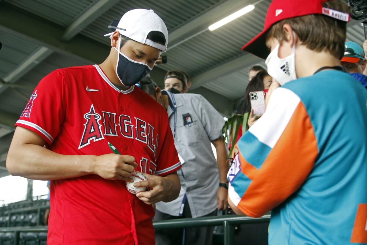 The Angels' Shohei Ohtani autographs a baseball for Palm City, Fla.'s Brennan Jones