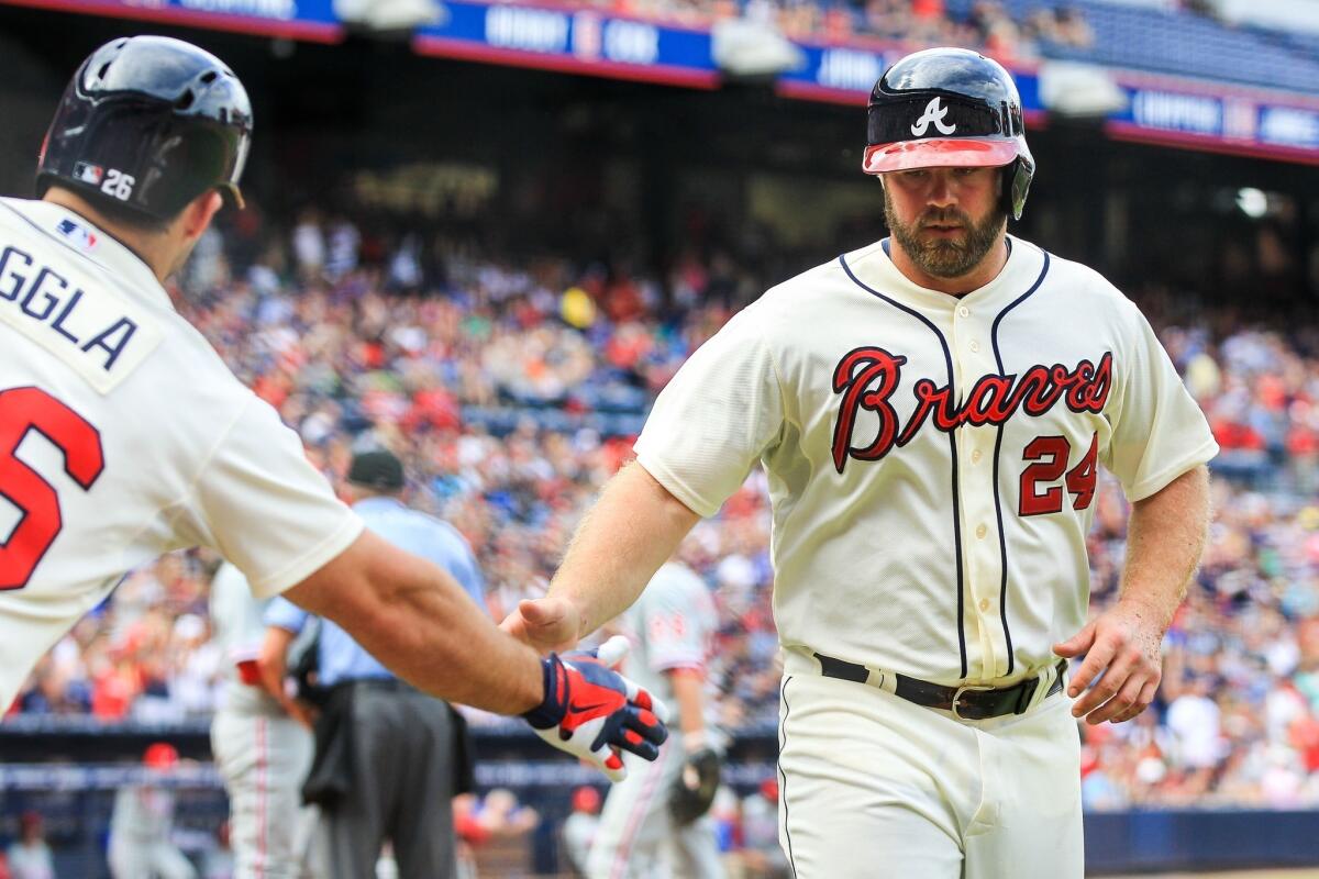 Atlanta's Evan Gattis, right, is congratulated by teammate Dan Uggla after scoring a run against the Philadelphia Phillies on Sunday. Some players on the Braves are upset the Dodgers are favored by some to win their National League division series playoff.