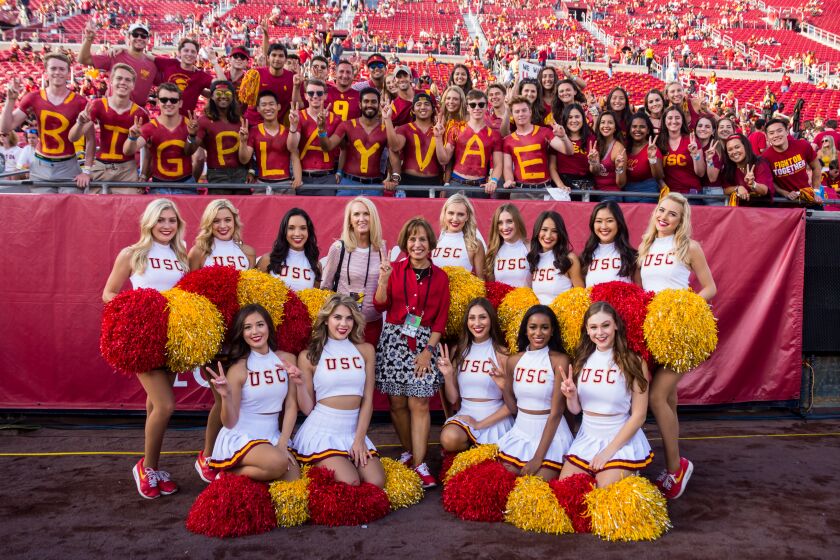 USC president Carol Folt (in red), center, poses with Lori Nelson (pink blouse) and the USC Song Girls.