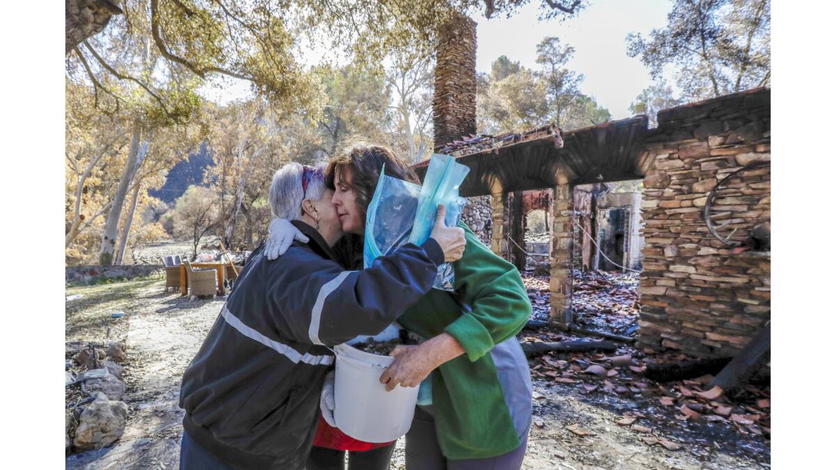 Search dog handler Lynne Engelbert, left, hugs sisters Shepha Schneirsohn Vainstein (hidden) and Karen Sorensen after giving them a bucket carrying their mother's cremated remains recovered from Vainstein's home in Thousand Oaks.