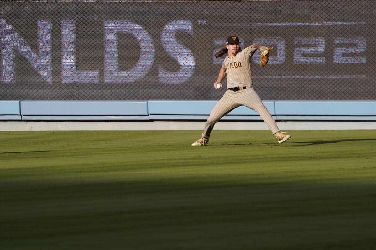 Padres pitcher Mike Clevinger warms up in the outfield during a workout Monday in Los Angeles.