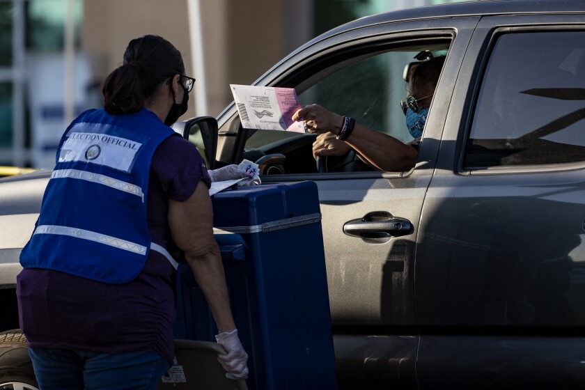 RIVERSIDE, CA - OCTOBER 30, 2020: A voter drops off her ballot during a drive-thru ballot drop-off at the Registrar of Voters Office on October 30, 2020 in Riverside, California. There was a steady line of cars up until the 5pm closing time.(Gina Ferazzi / Los Angeles Times)