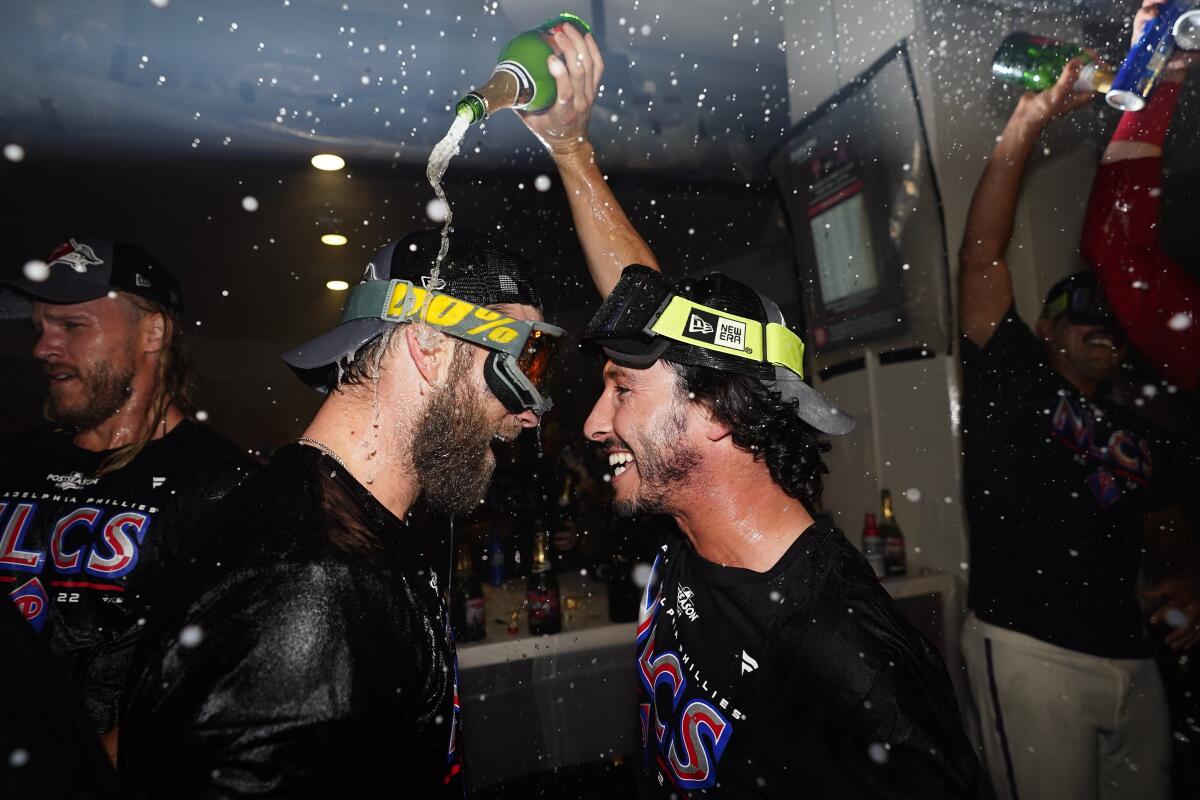 Bryce Harper, bateador designado de los Filis de Filadelfia, es bañado con champaña