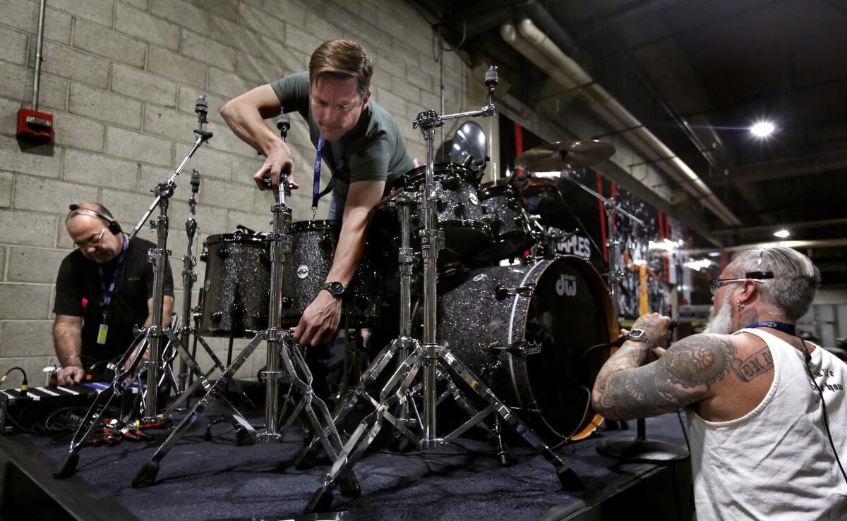 From left: Audio assistant Pete San Filipo, back line tech Ben Fenton and audio assistant Damon Andres get gear set up and check microphones on a drum riser that will be used for a performance by Lionel Richie during the Grammy Awards show.