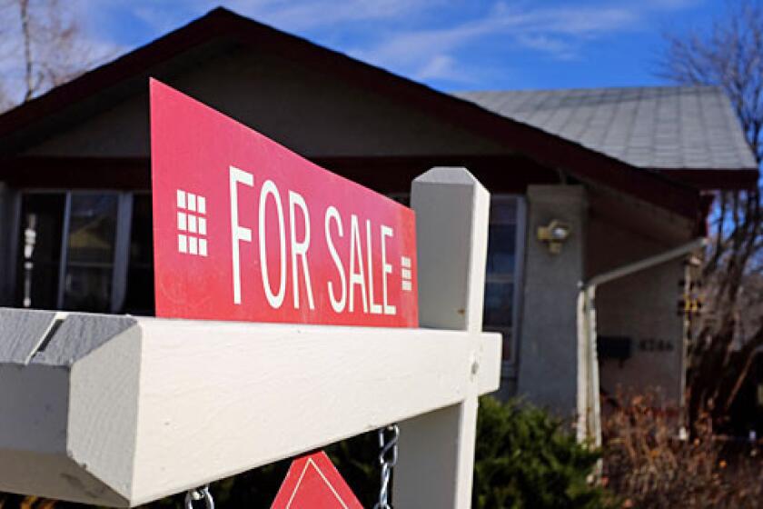 A "For Sale" sign stands in the yard of a single family home in Denver, Colorado.