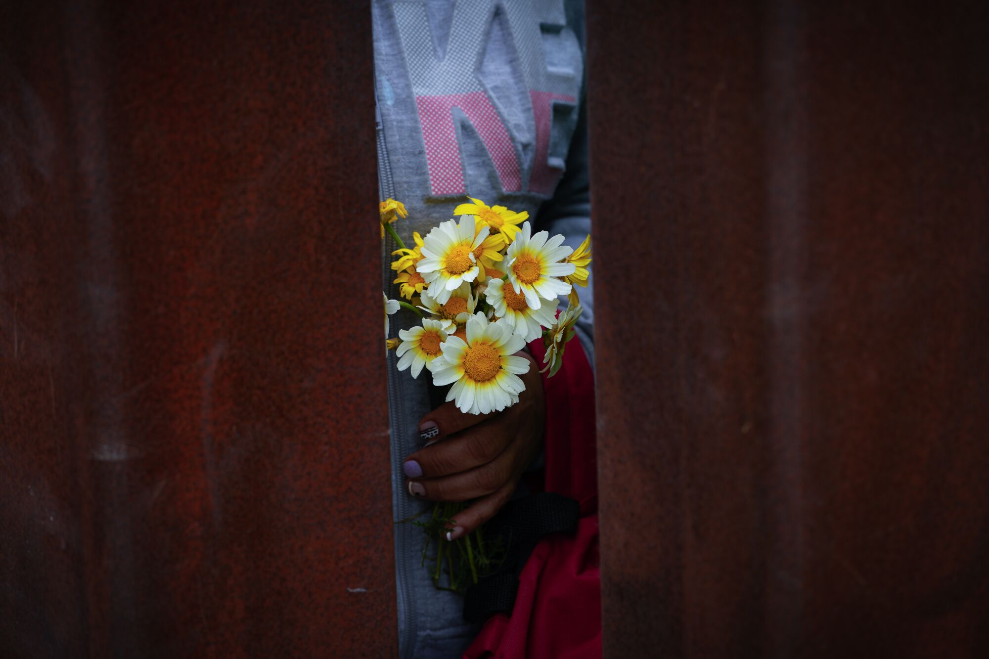 A woman at the encampment along the U.S. Mexico border held a small bouquet of wild flowers.