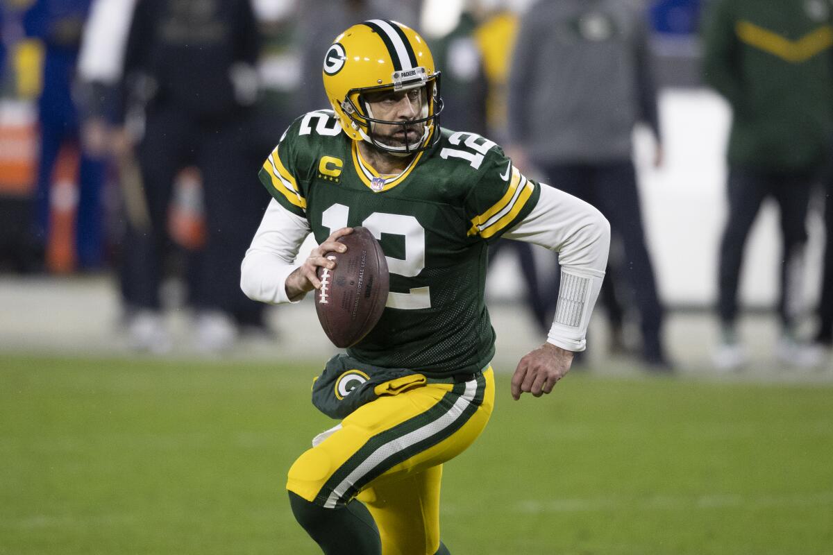 FILE - In this Jan. 16, 2021, file photo, Green Bay Packers quarterback Aaron Rodgers (12) runs with the ball during the team's NFL divisional playoff football game against the Los Angeles Rams in Green Bay, Wis. Green Bay Packers quarterback Aaron Rodgers’ teammates say the MVP’s uncertain status won’t distract them in their offseason preparations. Rodgers hasn’t been present for organized team activities this week following an ESPN report last month that he doesn’t want to return to Green Bay. Rodgers was noncommittal about his future in an ESPN interview Monday night, May 24, 2021.(AP Photo/Jeffrey Phelps, File)