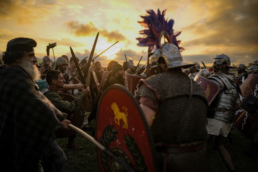 Participants in the Romula Fest historic reenactment event clash during a battle in the village of Resca, Romania, Saturday, Sept. 3, 2022. Members of historic NGOs and volunteers gathered in a field outside a southern Romanian village, once part of the Romula Malva, Roman Empire era city, aiming to raise awareness for history through realistic reenactments of battles between Roman legions and local Dacian tribes.(AP Photo/Andreea Alexandru)
