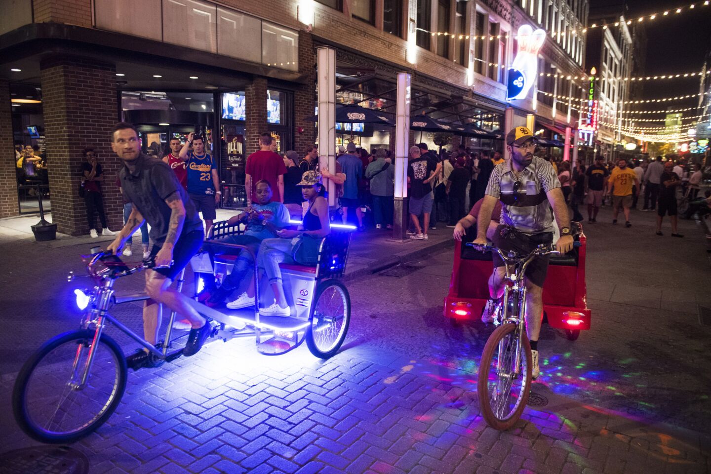 Rickshaws make their way down East 4th Street as fans watch the Cleveland Cavaliers on TVs in the lo