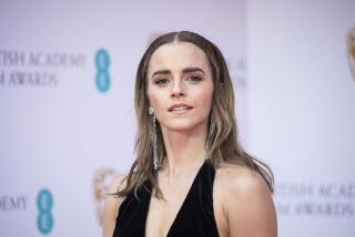 Emma Watson poses in dangly earrings and a black dress.