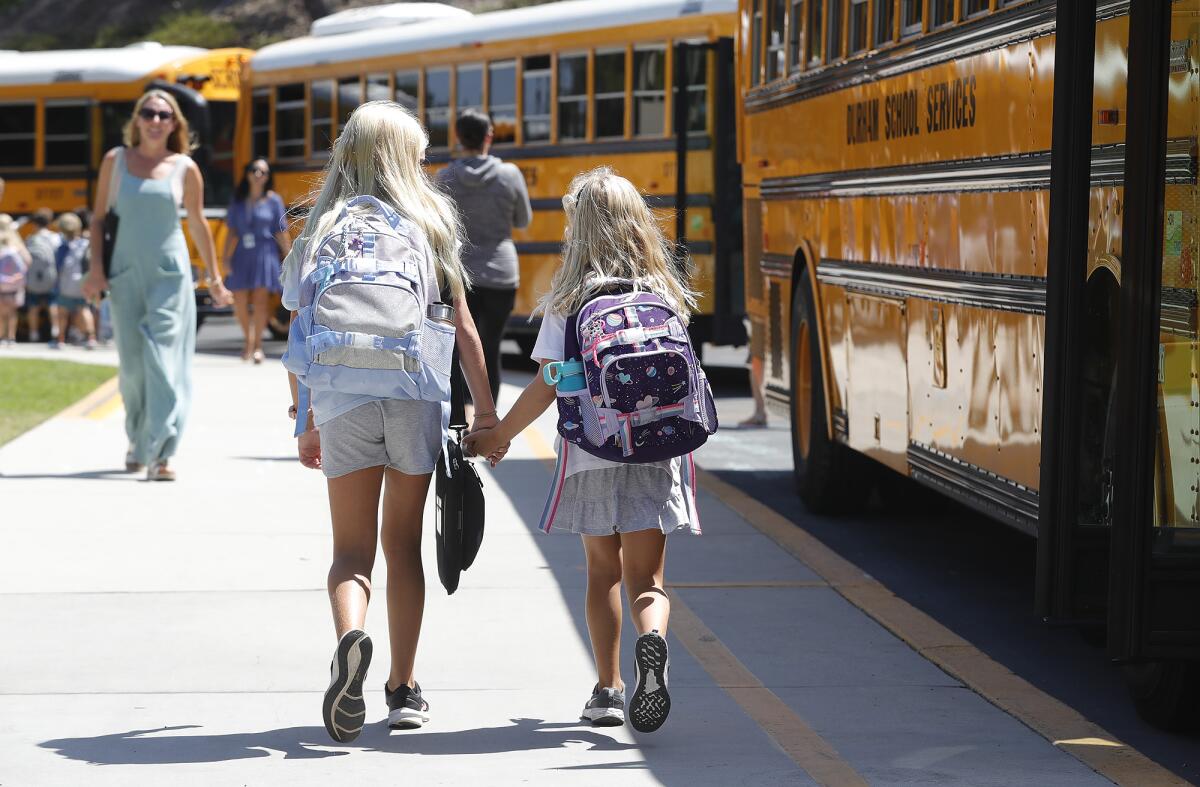 Two third-graders find their home bus during the first day of class at Top of the World Elementary in Laguna Beach.