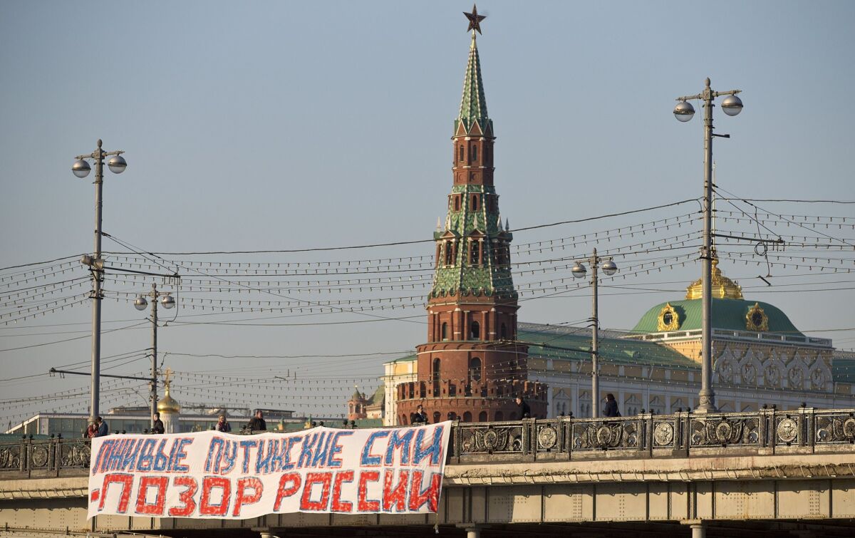 A banner reading "Putin's lying media are the shame of Russia" hangs from a bridge near the Kremlin on Friday. The Russian government has refused to renew a broadcasting license for Voice of America, adding the U.S.-funded news and cultural programmer to the list of media silenced by the Kremlin.