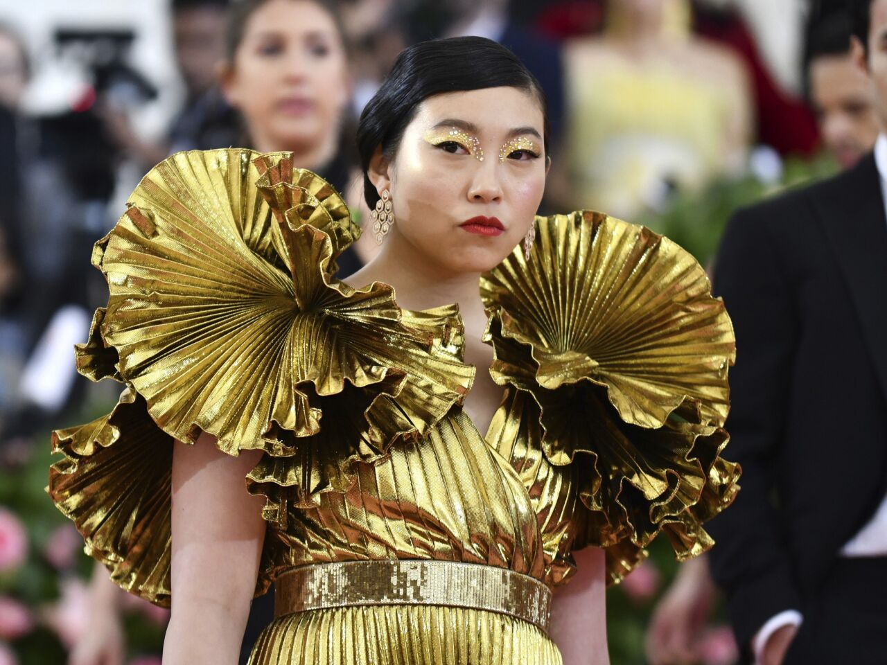 Awkwafina's gold eye makeup continues the theme of her Altuzarra gown.