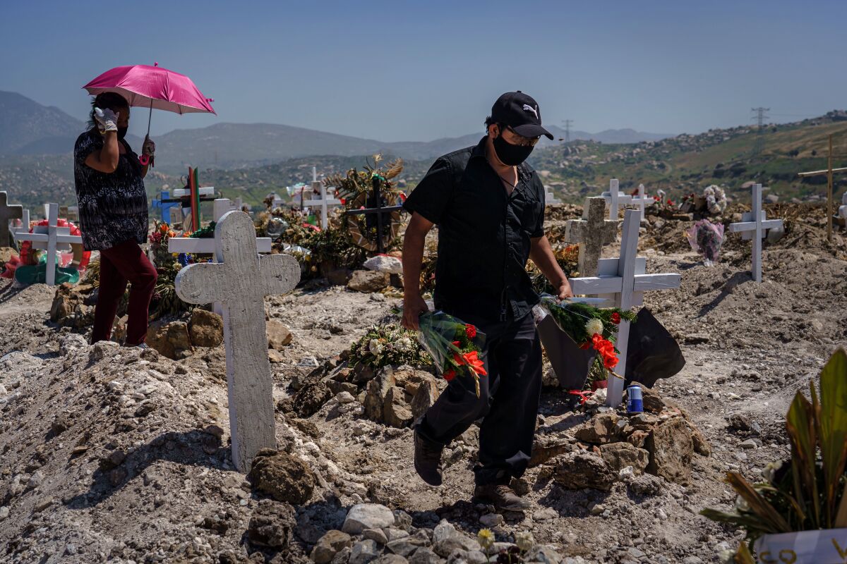 A relative arrives with flowers for the burial of Juan Velasco at a cemetery in Tijuana on April 27, 2020.
