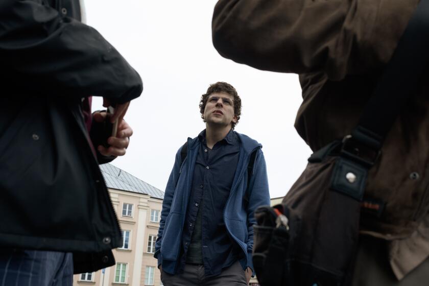 A man in a blue shirt stands on a movie set.