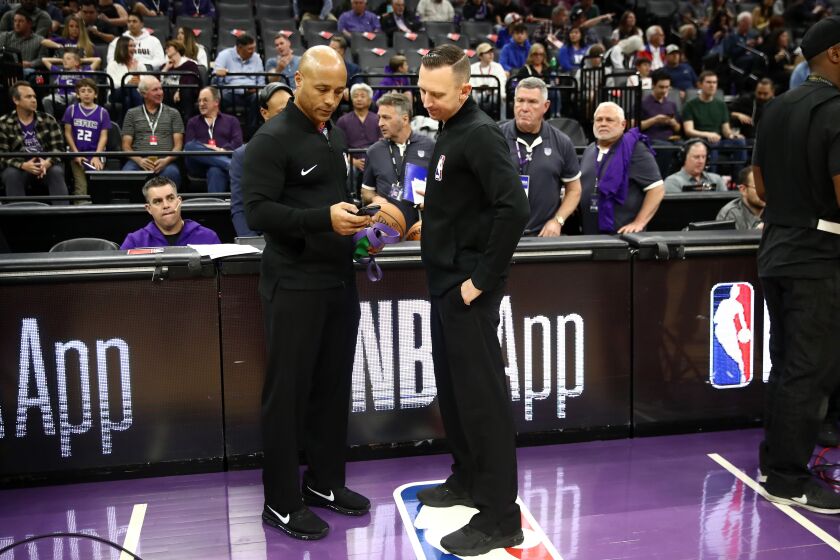 SACRAMENTO, CALIFORNIA - MARCH 11: Referee Marc Davis (left) looks at his phone as he stands next to Justin Van Duyne at mid-court before the Sacramento Kings game against the New Orleans Pelicans at Golden 1 Center on March 11, 2020 in Sacramento, California. The game was postponed due to the corona virus. NOTE TO USER: User expressly acknowledges and agrees that, by downloading and or using this photograph, User is consenting to the terms and conditions of the Getty Images License Agreement. (Photo by Ezra Shaw/Getty Images)