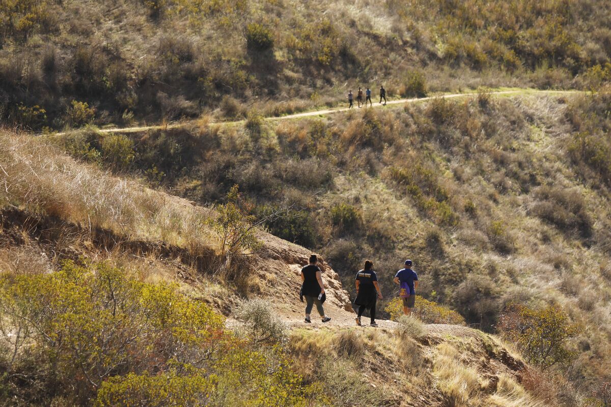 Hikers walk on a trail in Solstice Canyon.