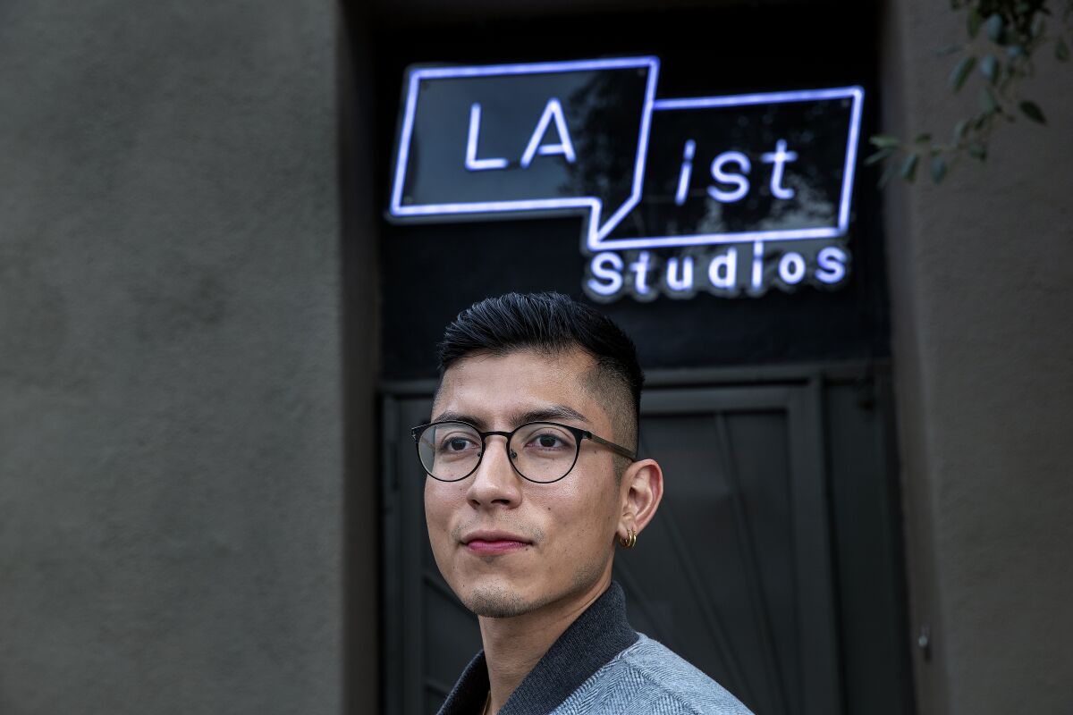 A man wearing glasses stands in front of an outdoor neon sign that says LAist Studios.