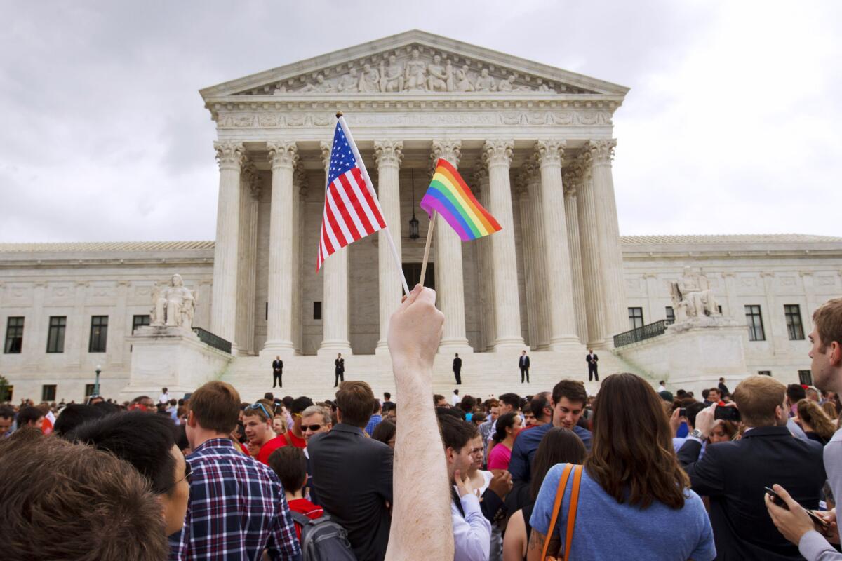 A man holds a U.S. and a rainbow flag outside the Supreme Court on June 26, after the court legalized gay marriage nationwide. A federal appeals court ruled Friday that the Supreme Court can keep protesters off its marble plaza without violating their constitutional right to free speech.