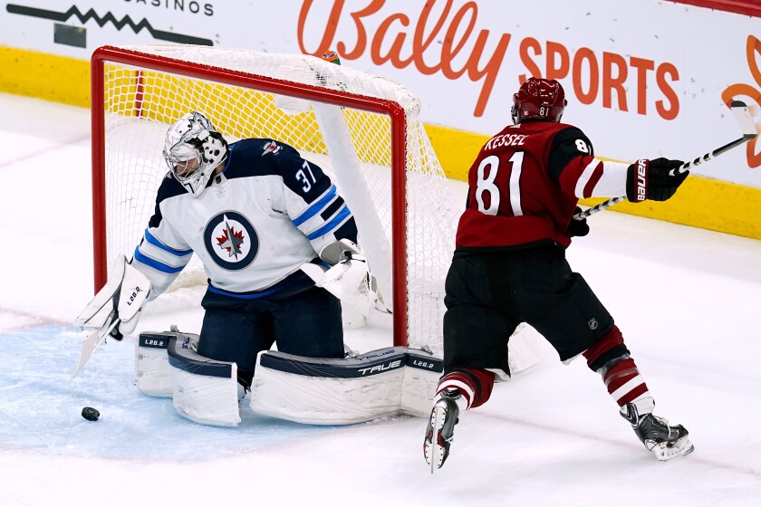 Winnipeg Jets goaltender Connor Hellebuyck (37) makes a save on a shot by Arizona Coyotes right wing Phil Kessel (81) during the first period of an NHL hockey game Tuesday, Jan. 4, 2022, in Glendale, Ariz. (AP Photo/Ross D. Franklin)