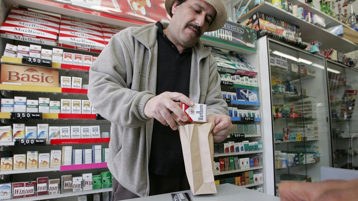 Shop owner Izzat Asfour sells a pack of cigarettes to a customer in San Francisco.