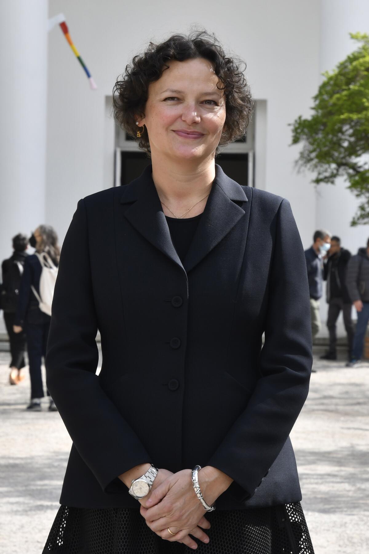 A woman in a black blazer smiles