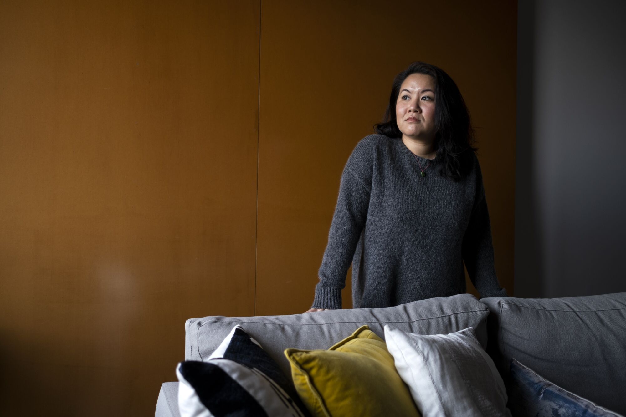 Portrait of Thanh Tan, standing behind a couch 