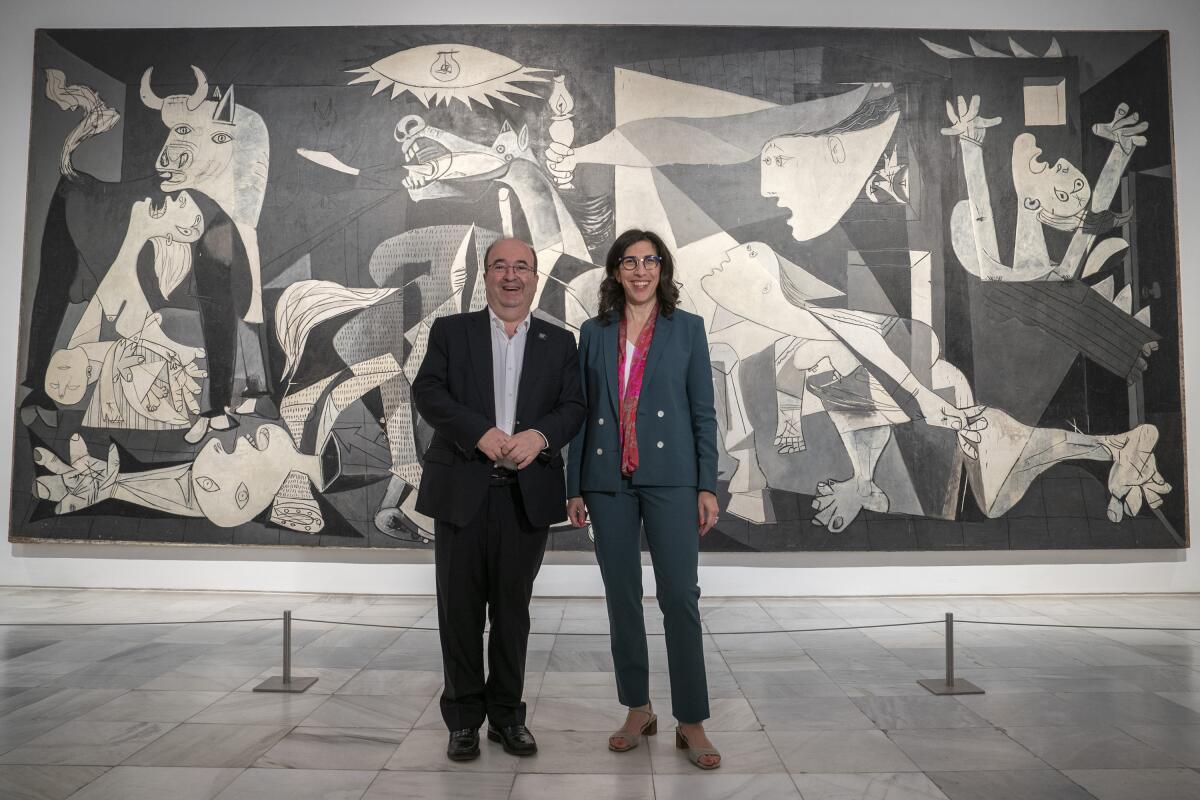 French Culture Minister Rima Abdul-Malakin, right, poses for a picture next to his Spanish counterpart Miquel Iceta during a joint news conference in front of Pablo Picasso's "Guernica" painting to present the "Picasso Year" events, marking the 50th anniversary of the painter's death, at the Reina Sofia Museum in Madrid, Spain, Monday, Sept. 12, 2022. Against the backdrop of Picasso's iconic anti-war painting, "Guernica," the culture ministers of France and Spain have gathered in Madrid to kick off a year of commemorative acts to celebrate the 50th anniversary of the death of the Spanish artist who revolutionized the world of art. (AP Photo/Andrea Comas)