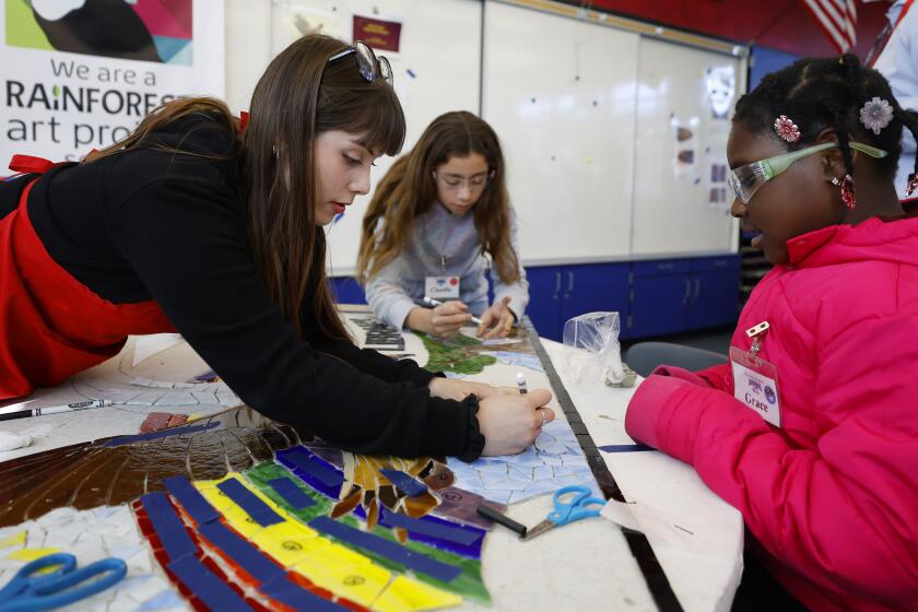 San Diego, CA - January 11: Vanessa Machin of the Rainforest Art Project works on a mosaic mural with fourth graders Claudia Silva, and Valentin Camargo at the school on Wednesday, January 11, 2023 in San Diego, CA. The mosaic is part of the Rainforest Art program which teaches students how to make art which is supported by the VAPA Foundation (K.C. Alfred / The San Diego Union-Tribune)