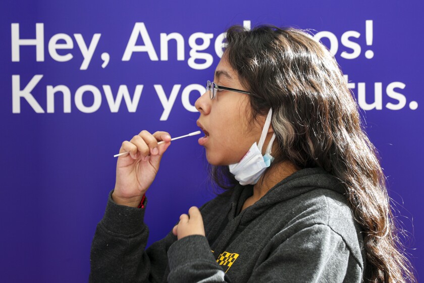 Laura Robles, 14, takes a self-administered oral swab COVID-19 test at Union Station in 2020.