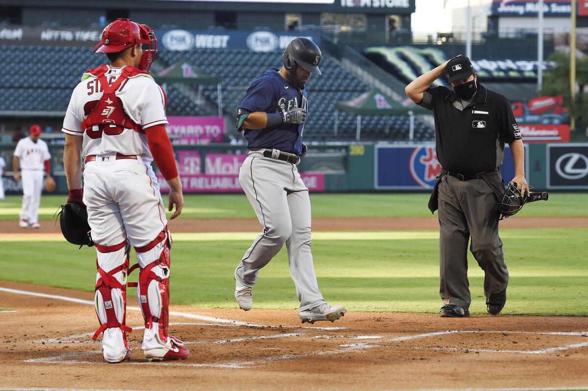 Seattle Mariners first baseman Jose Marmolejos, center, touches home plate after hitting a three-run home run.