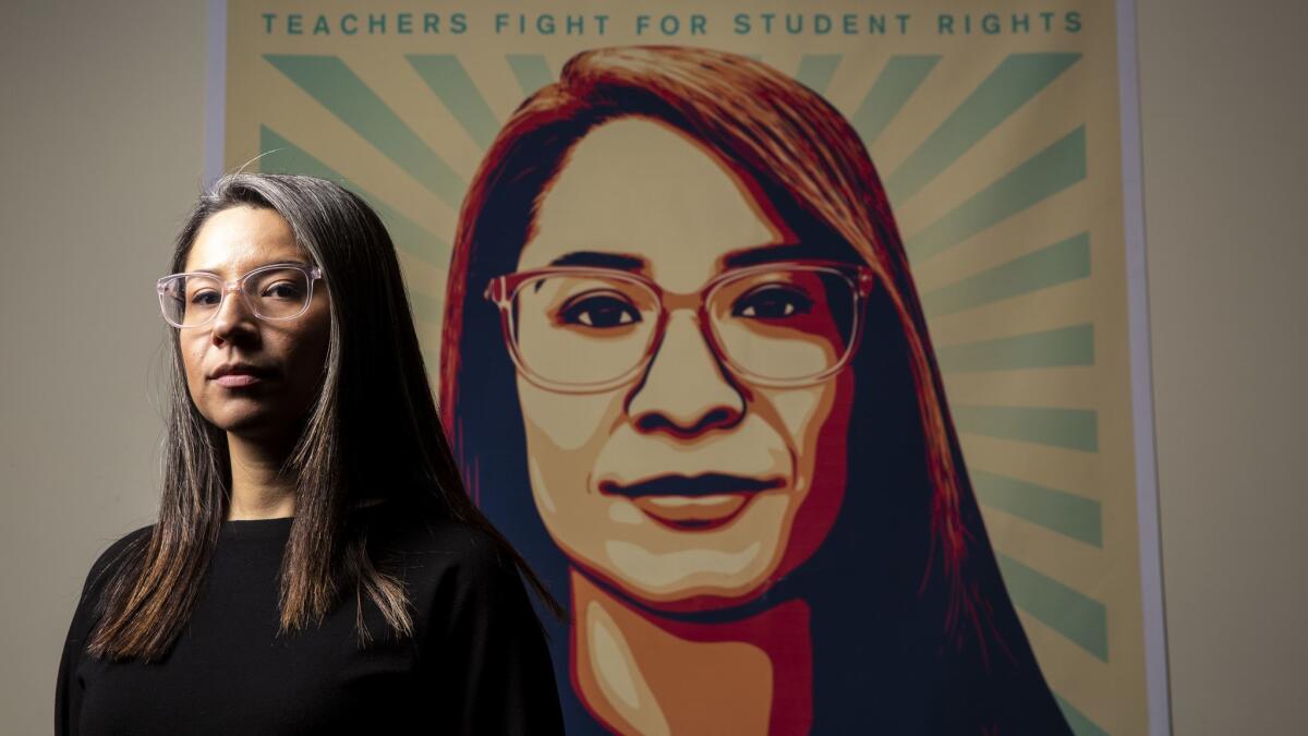 Roxana Duenas, whose face appears on the widely circulated "Stand With L.A. Teachers" poster, poses for a portrait in front of a large version of the poster at UTLA Headquarters.