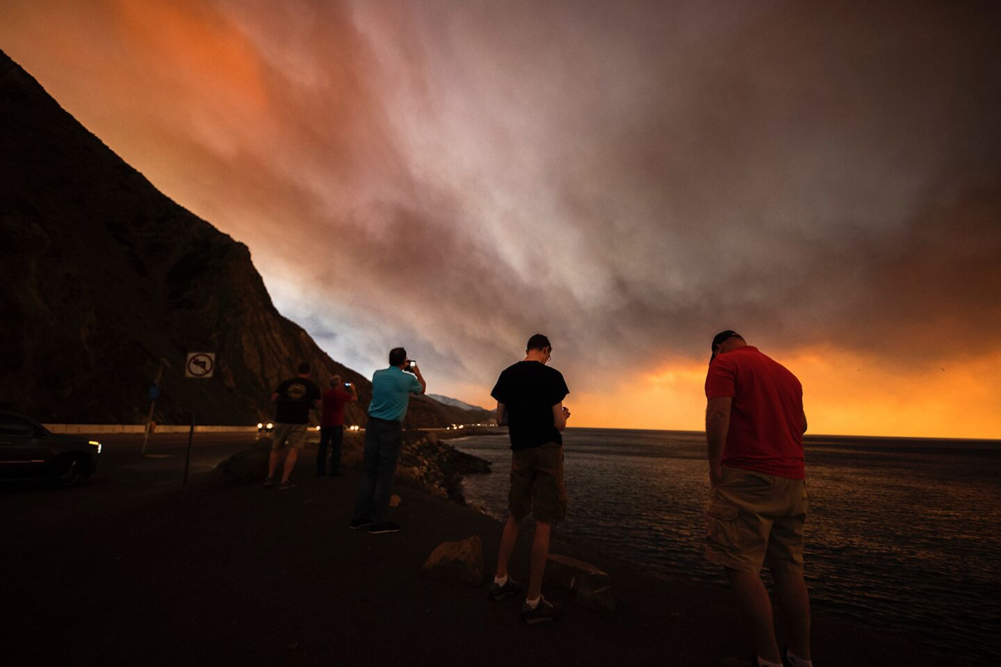 Onlookers watch smoke from the Woolsey fire and take photos on Pacific Coast Highway looking southeast toward Malibu on Friday.