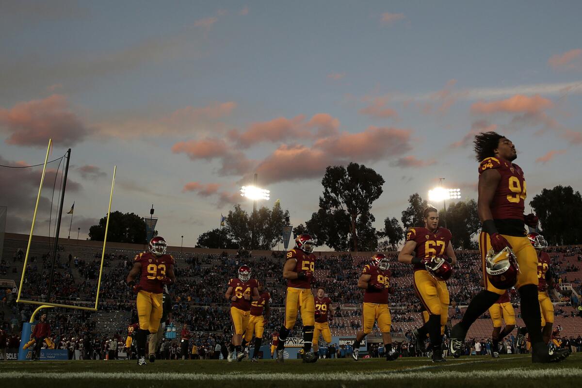USC defensive players jog off the field after warming up before a game against UCLA at the Rose Bowl.