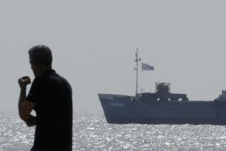 Un hombre en la playa mientras un barco cargado con toneladas de alimentos destinados para la Franja de Gaza navega por las aguas fuera del puerto de Larnaca, Chipre, el sábado 30 de marzo de 2024. (AP Foto/Petros Karadjias)