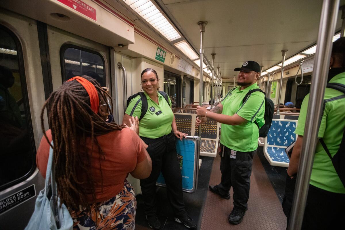 People in neon green T-shirts talk with a passenger aboard a Metro train.